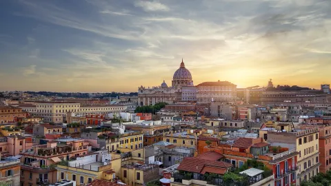 Sunset over the Papal Basilica of Saint Peter and the city buildings in Rome.